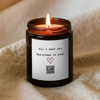 Hořící vánoční svíčka „Melodická“ Kiskedves, na etiketě kreslené srdce, QR kód a nápis All I want for Christmas is you
